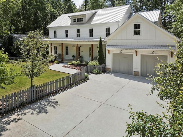 modern inspired farmhouse with a garage, board and batten siding, a porch, fence private yard, and driveway