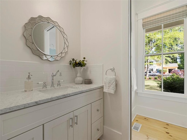 bathroom with backsplash, visible vents, a healthy amount of sunlight, and vanity