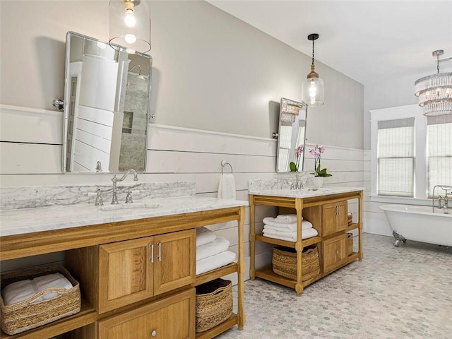 full bathroom with a freestanding tub, a chandelier, a wainscoted wall, and vanity