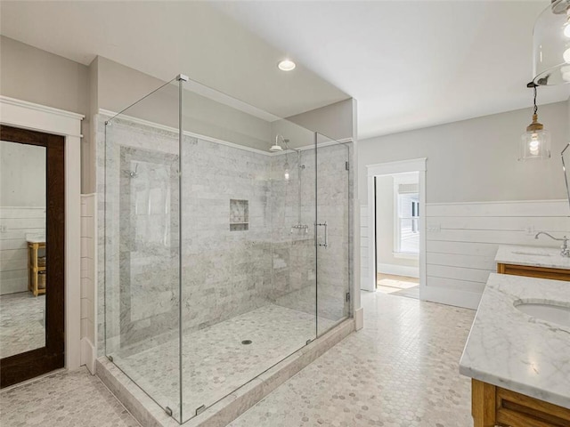 full bathroom featuring a sink, wainscoting, a stall shower, and double vanity