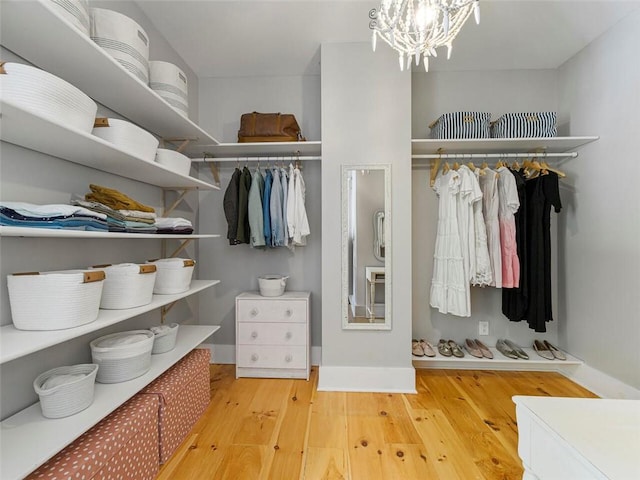 walk in closet featuring a notable chandelier and wood finished floors