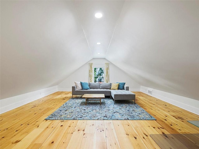living area featuring wood-type flooring, baseboards, visible vents, and lofted ceiling