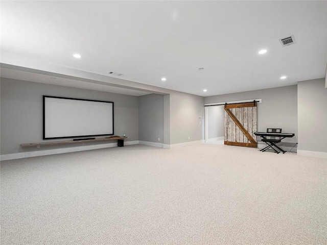 home theater room with light colored carpet, recessed lighting, a barn door, and visible vents