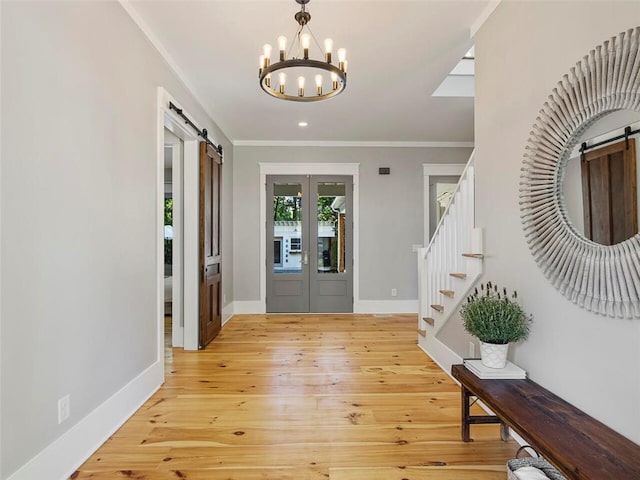 foyer with a chandelier, a barn door, ornamental molding, and stairway