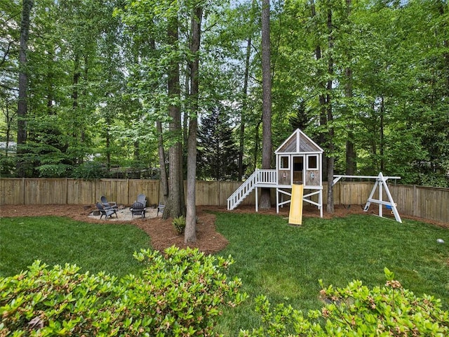 view of yard with a fenced backyard, a playground, and a fire pit