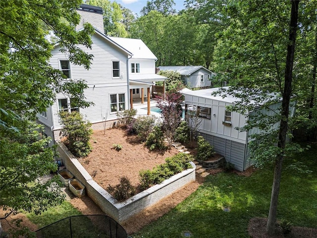 back of house featuring a chimney, a patio area, and an outdoor pool