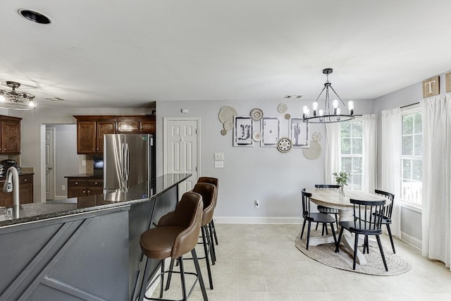 1751 Fire Side Ct, Jefferson, GA 30549 - kitchen featuring freestanding refrigerator, a chandelier, a kitchen breakfast bar, dark stone countertops, and decorative light fixtures