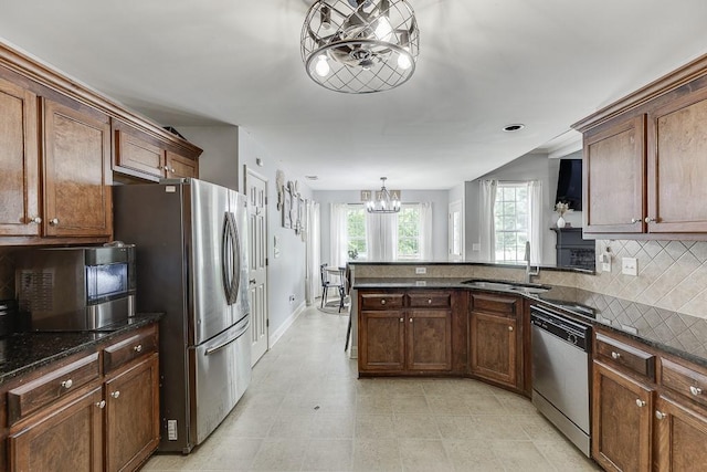 1751 Fire Side Ct, Jefferson, GA 30549 - kitchen featuring appliances with stainless steel finishes, a chandelier, tasteful backsplash, a peninsula, and dark stone counters