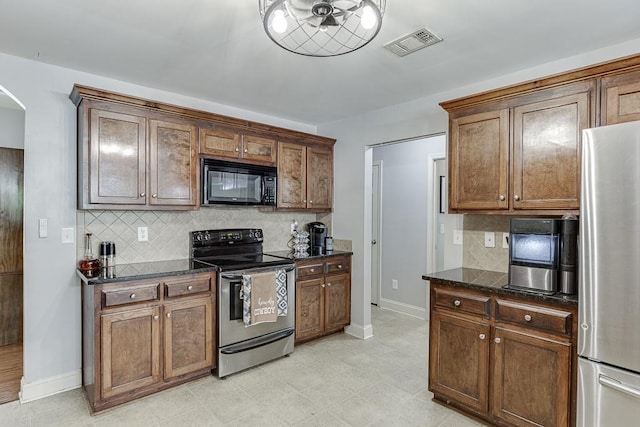 1751 Fire Side Ct, Jefferson, GA 30549 - kitchen featuring appliances with stainless steel finishes, backsplash, arched walkways, dark stone counters, and light flooring