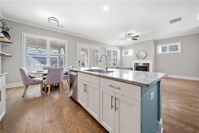 kitchen with visible vents, dishwasher, crown molding, a fireplace, and a sink