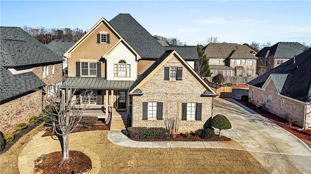 view of front of house with a porch, a shingled roof, brick siding, stucco siding, and a standing seam roof