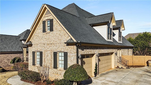 view of home's exterior with an attached garage, brick siding, a shingled roof, fence, and driveway