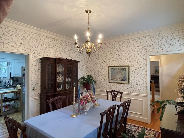 dining space with ornamental molding, a chandelier, and hardwood / wood-style floors