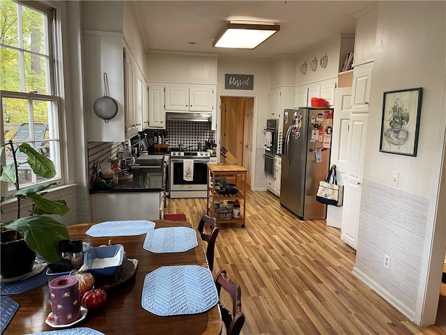 kitchen with white cabinetry, stainless steel appliances, light wood-type flooring, and a healthy amount of sunlight