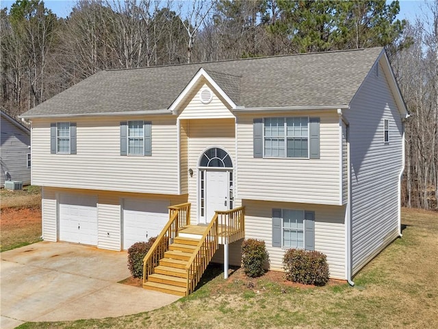 split foyer home featuring central AC, roof with shingles, concrete driveway, a front yard, and an attached garage