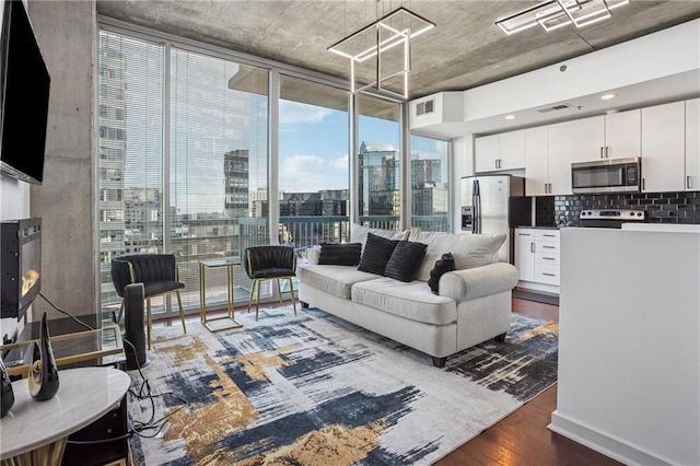 living area with floor to ceiling windows, a city view, visible vents, and wood finished floors