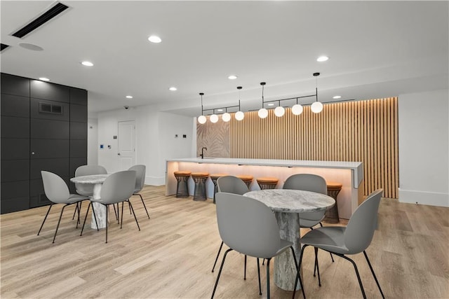 dining room with light wood-type flooring, visible vents, indoor wet bar, and recessed lighting