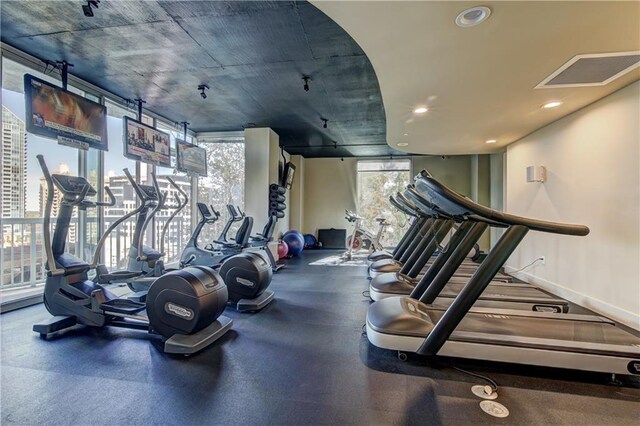 exercise room featuring baseboards, a wall of windows, visible vents, and recessed lighting