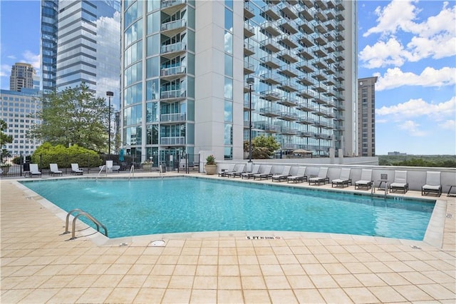 pool with a patio area, a view of city, and fence