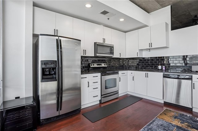 kitchen featuring dark wood-style floors, dark countertops, visible vents, backsplash, and appliances with stainless steel finishes