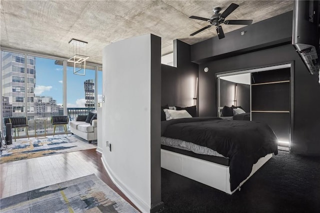 bedroom with baseboards, wood finished floors, access to exterior, a view of city, and floor to ceiling windows