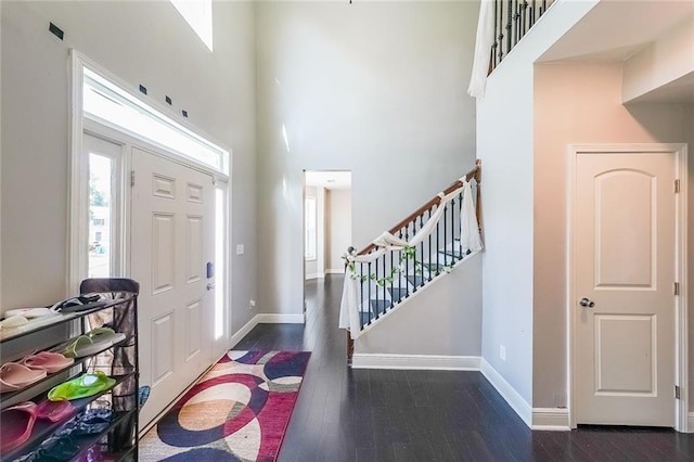 entrance foyer featuring baseboards, stairs, wood finished floors, and a towering ceiling