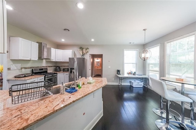 kitchen with baseboards, wall chimney exhaust hood, white cabinets, dark wood finished floors, and stainless steel appliances