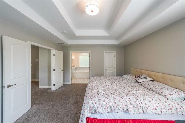 carpeted bedroom featuring baseboards, ensuite bathroom, a tray ceiling, and visible vents