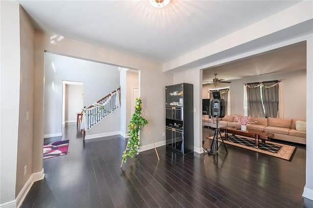 living area featuring stairway, baseboards, wood-type flooring, and a ceiling fan