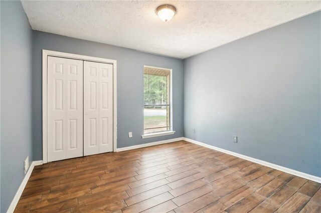 unfurnished bedroom with a closet, dark hardwood / wood-style floors, and a textured ceiling