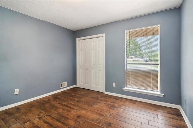 unfurnished bedroom featuring dark hardwood / wood-style flooring and a closet