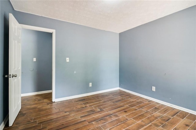 spare room with dark wood-type flooring and a textured ceiling