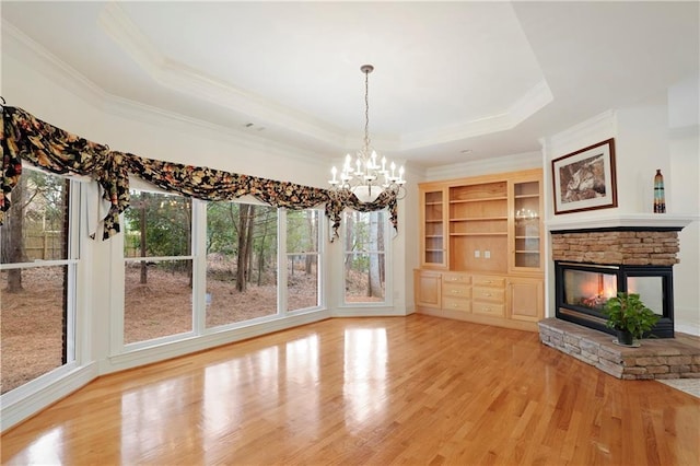 unfurnished living room with a raised ceiling, light hardwood / wood-style flooring, a fireplace, and a wealth of natural light