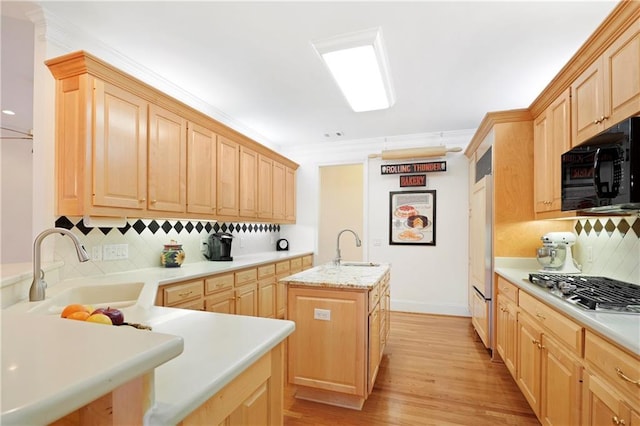 kitchen featuring light brown cabinets, a center island with sink, and tasteful backsplash