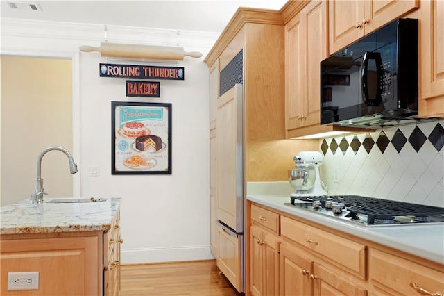 kitchen with light hardwood / wood-style floors, tasteful backsplash, ornamental molding, sink, and stainless steel gas cooktop