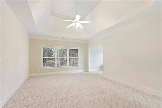 empty room with crown molding, light colored carpet, ceiling fan, and a tray ceiling