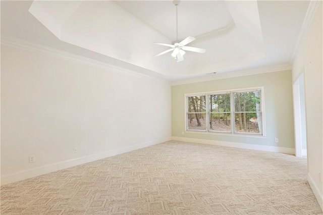 carpeted spare room with a raised ceiling, ceiling fan, and crown molding