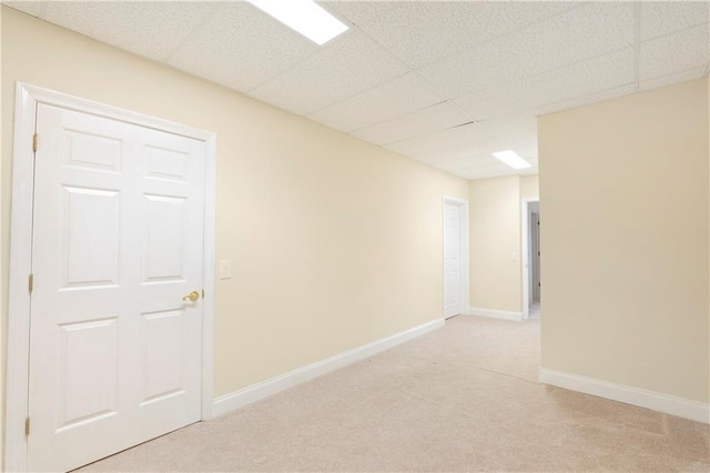 unfurnished room featuring a drop ceiling and light colored carpet