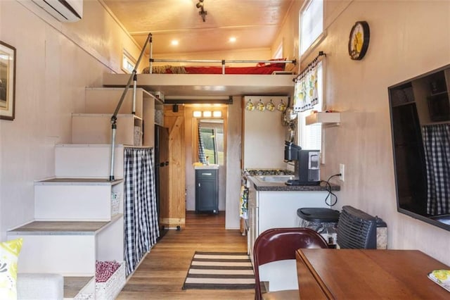 kitchen featuring dark countertops, a wall unit AC, and light wood-style flooring