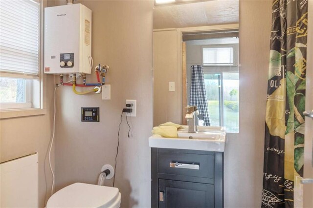 full bathroom featuring toilet, tankless water heater, and a sink