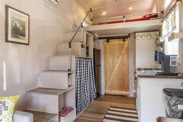 kitchen with dark countertops, a barn door, and wood finished floors