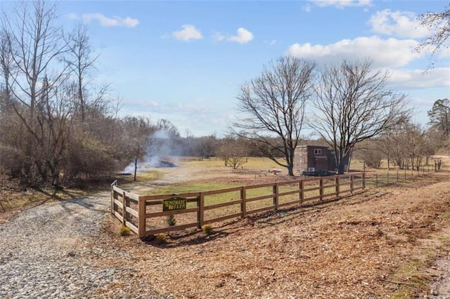 view of yard featuring a rural view, gravel driveway, and fence