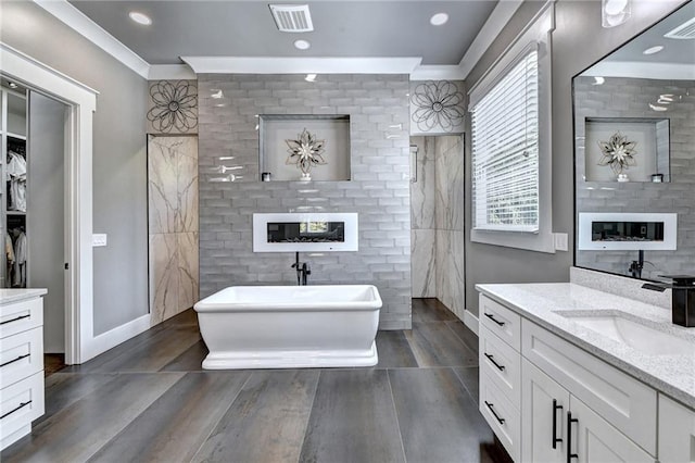 bathroom with a bathing tub, vanity, hardwood / wood-style floors, and crown molding