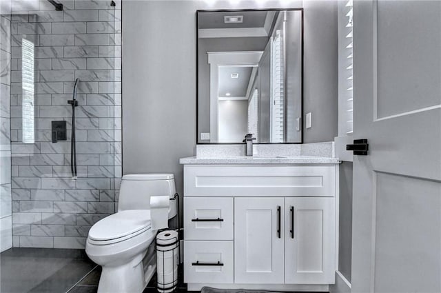 bathroom featuring vanity, tiled shower, and toilet