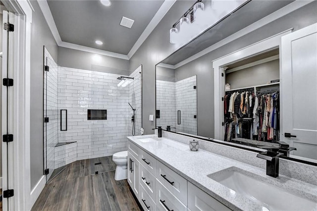 bathroom with toilet, walk in shower, crown molding, hardwood / wood-style floors, and vanity