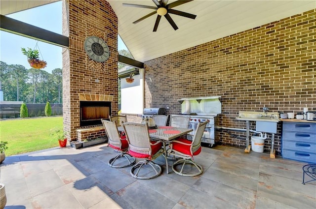 view of patio / terrace with ceiling fan, an outdoor brick fireplace, area for grilling, and exterior kitchen