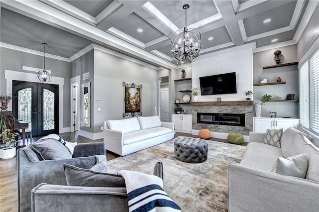 living room with a high end fireplace, french doors, a chandelier, crown molding, and hardwood / wood-style floors