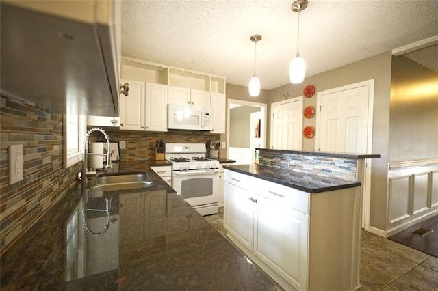 kitchen with decorative backsplash, white appliances, sink, white cabinetry, and hanging light fixtures