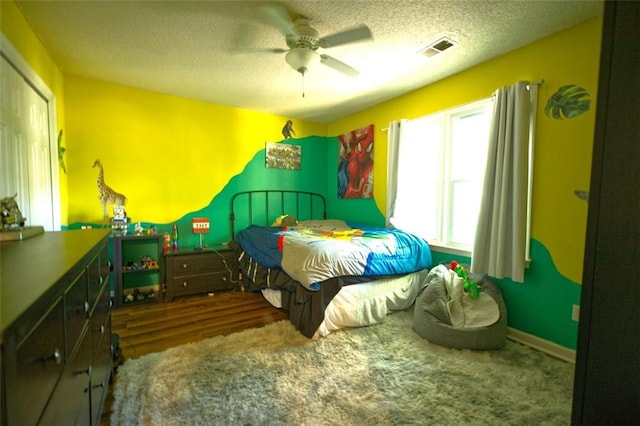 bedroom with ceiling fan, a textured ceiling, and dark colored carpet