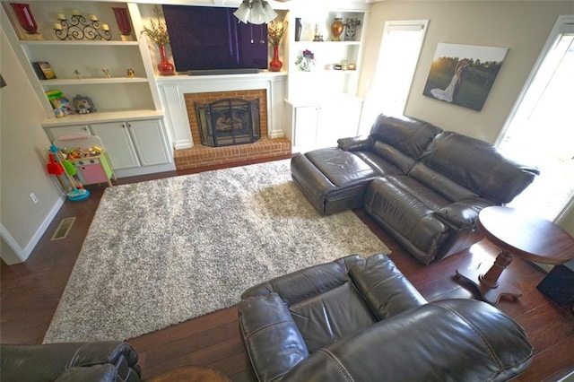 living room with built in shelves, ceiling fan, dark hardwood / wood-style flooring, and a fireplace